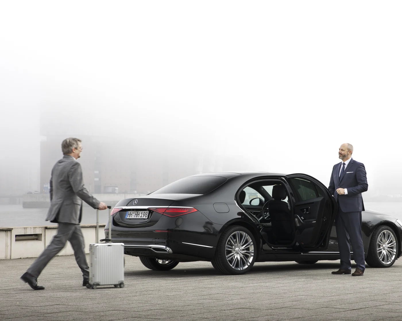Chauffeur empfängt einen Gast mit Gepäck an der Mercedes S-Klasse – Flughafentransfer in Hamburg